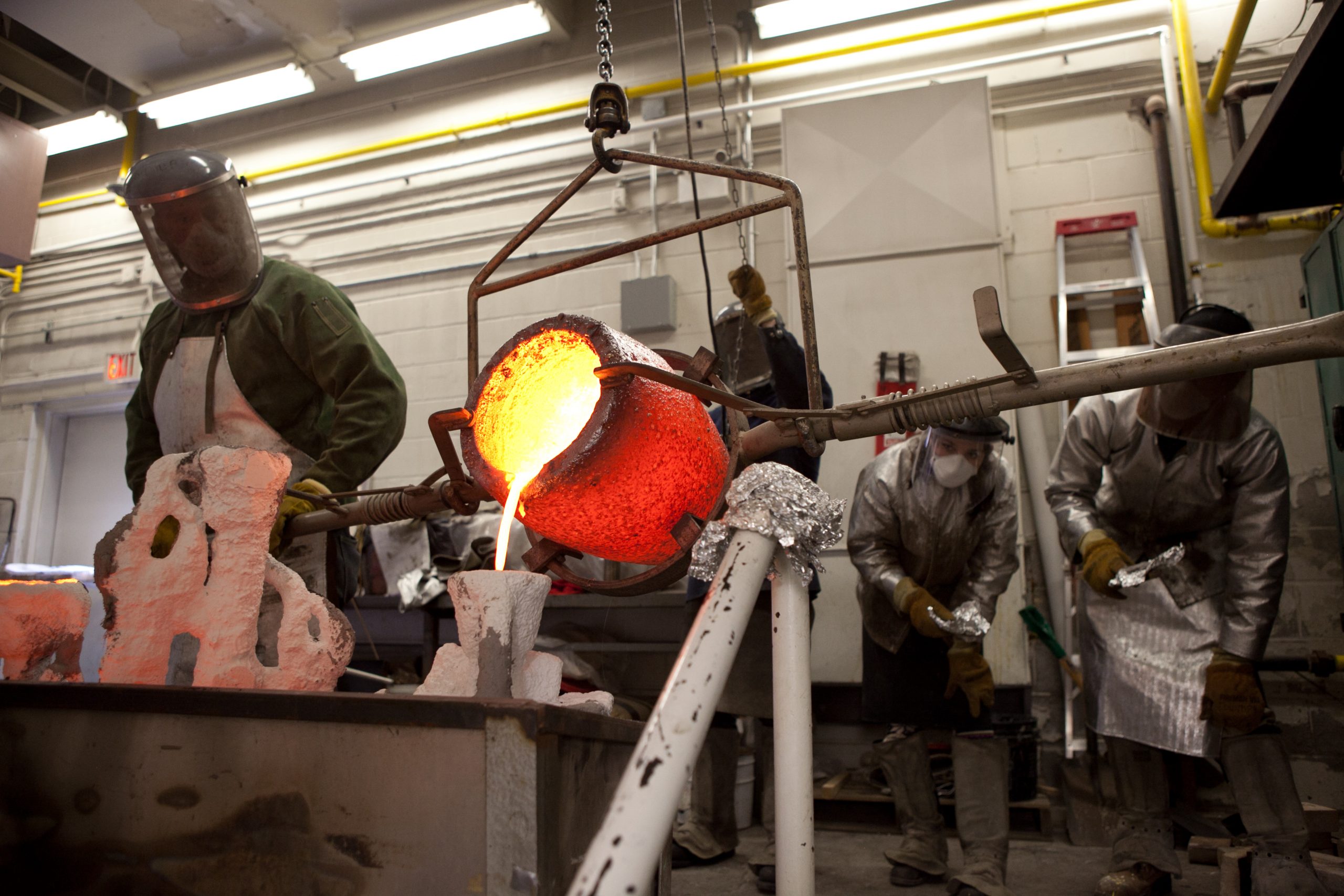 OCAD University's foundry: Artists in protective gear pouring metal into mould.