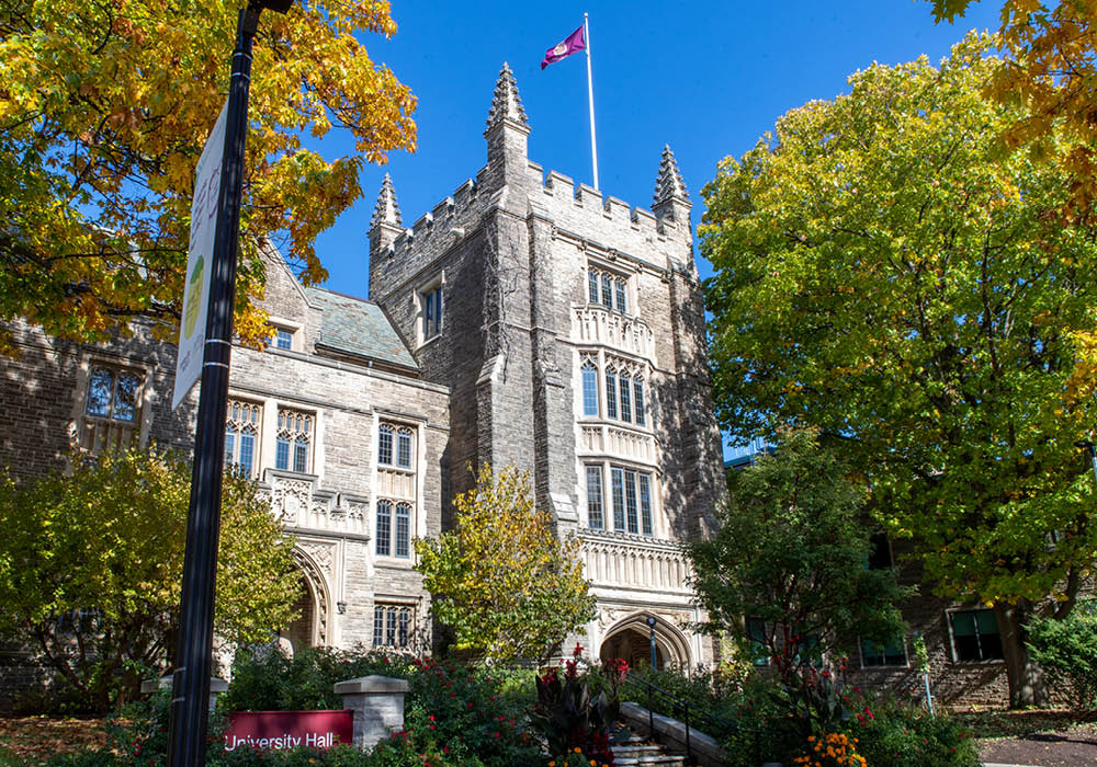 A picture of University Hall surrounded by green trees with a McMaster University flag raised.