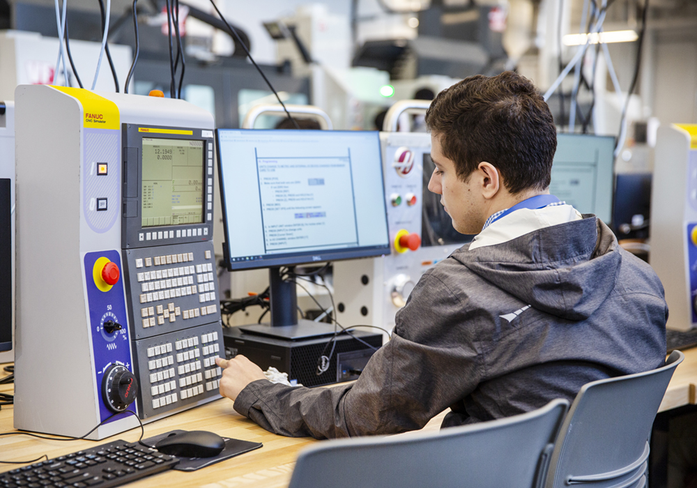 A male student is gaining practical experience in the Aerospace Manufacturing Engineering Technology lab at Centennial College's Downsview Campus: Centre for Aerospace and Aviation.