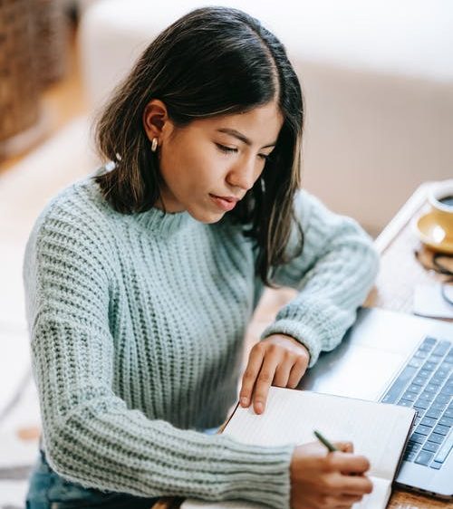 Student sitting at their desk making notes in a notebook