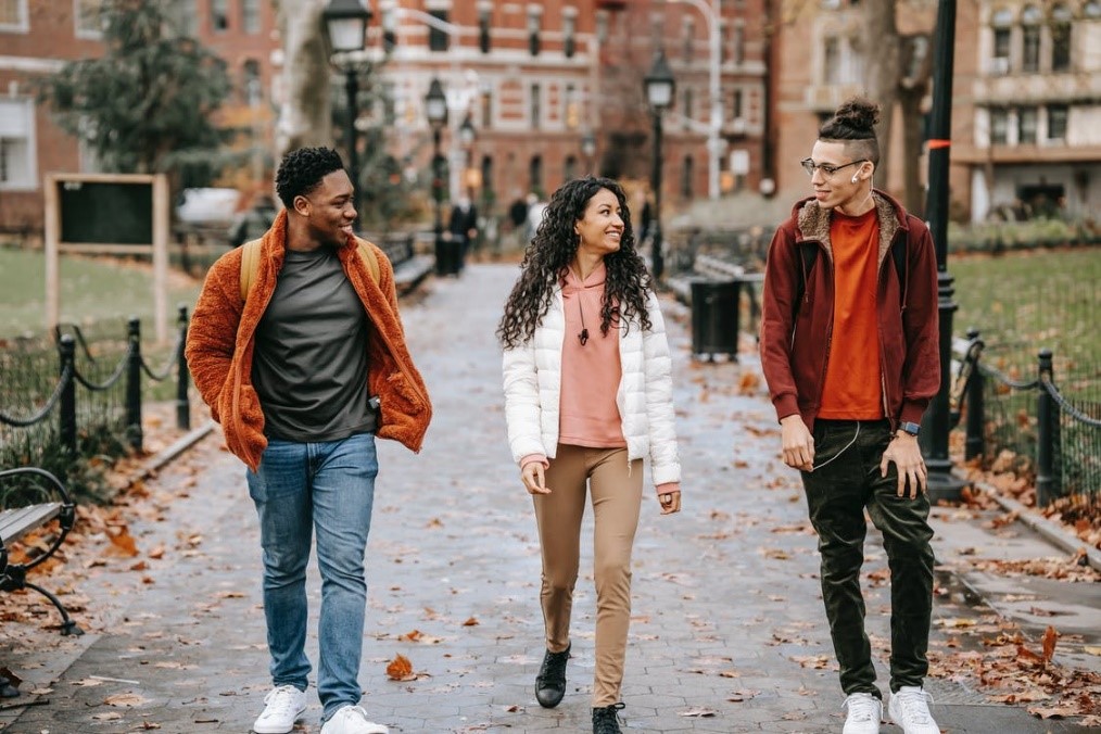 Three students walking on a path outside a school building