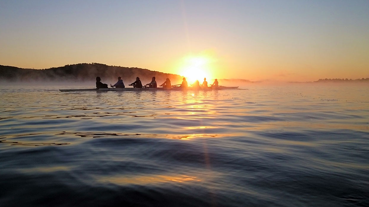 The Nipissing University rowing team on Trout Lake in North Bay on a beautiful morning in front of the sunrise